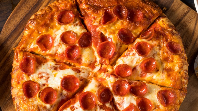pepperoni pizza on board with snacks