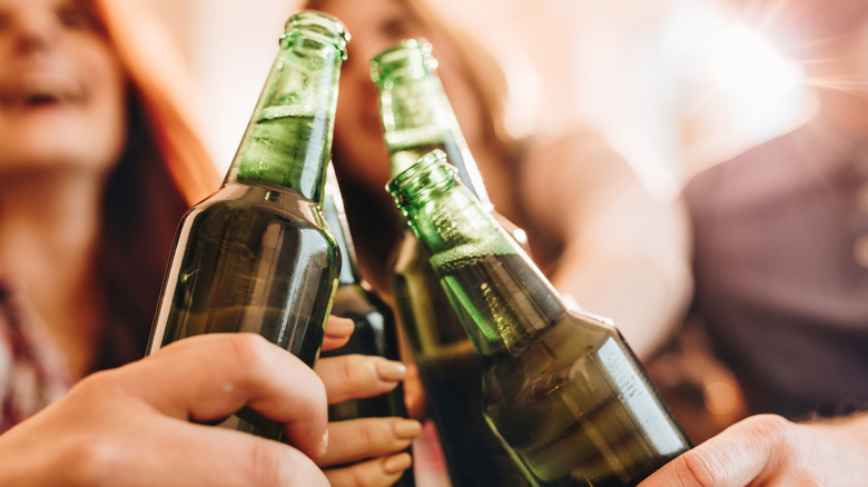 people toasting with bottles of beer