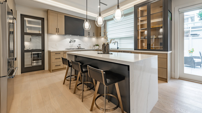 A sleek kitchen with pendant lights features a marble kitchen island with unique seats