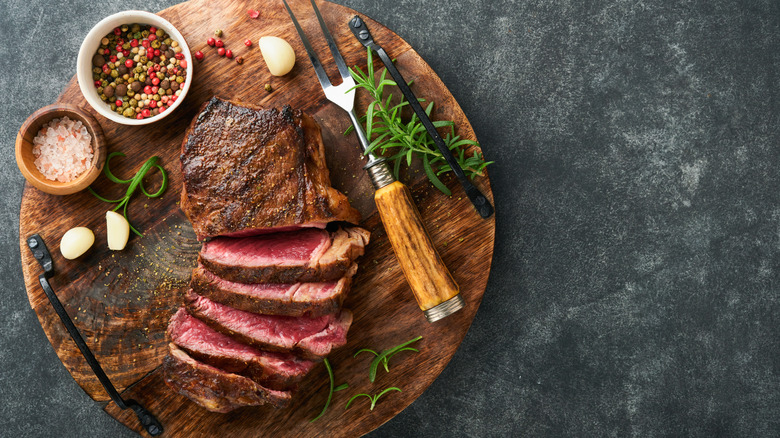 sliced new york strip with garnish spices on side