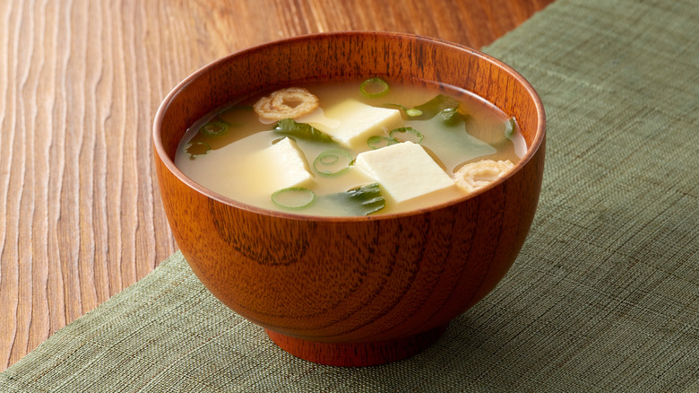A bowl of miso soup with tofu and seaweed.