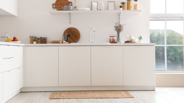 A kitchen with a small rug.