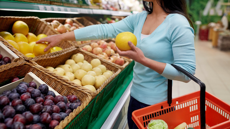 Woman selecting a grapefruit at market