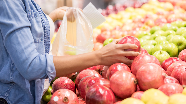 person choosing a pomegranate in store 