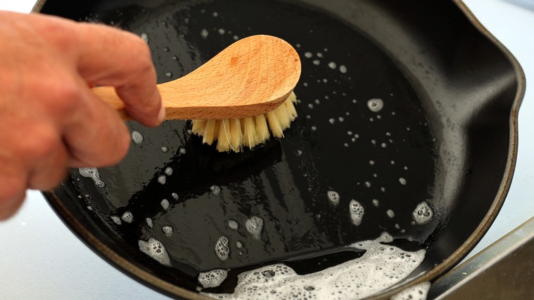 scrubbing cast iron pan with brush