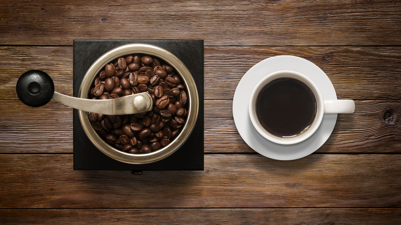 coffee grinder and a cup of coffee on wooden background