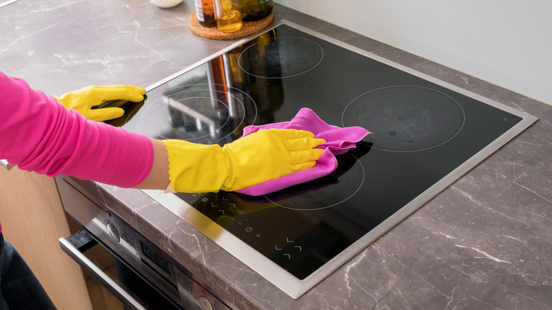 Person wiping glass top stove