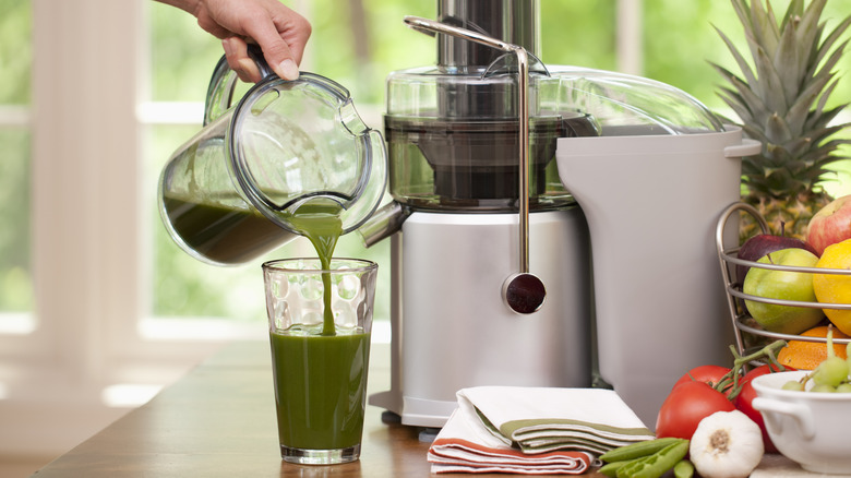person pouring juice out of a juicer container
