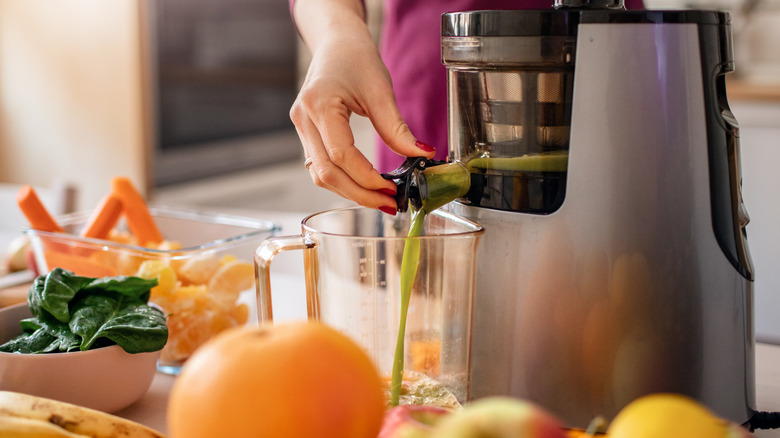 person making green juice with a juicer