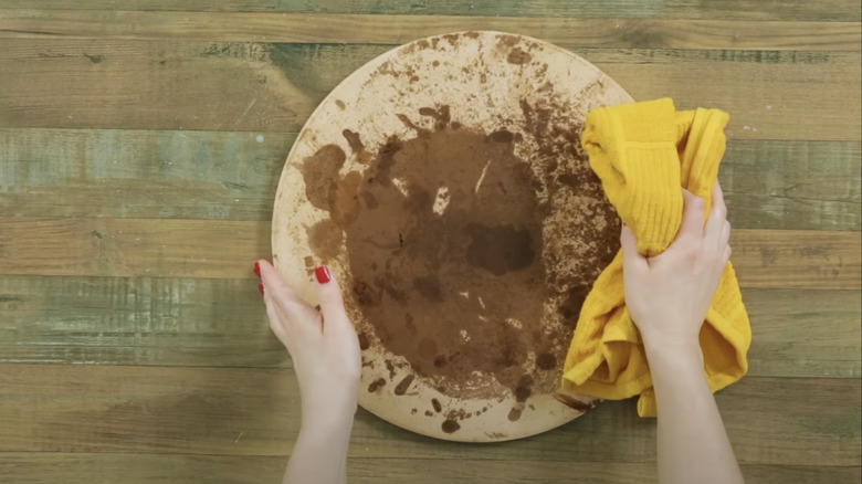 Hands cleaning stained pizza stone