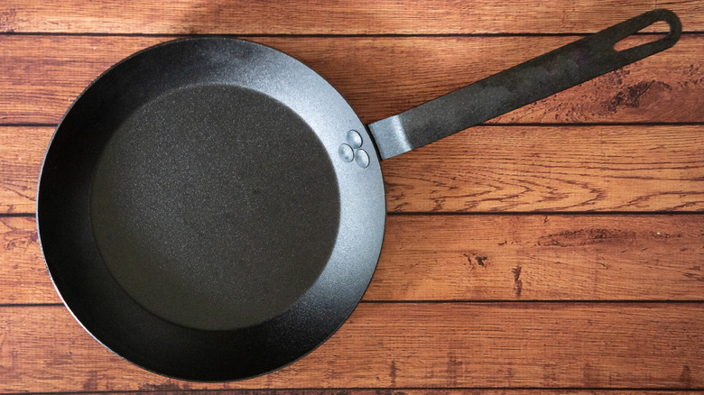 Clean carbon steel skillet on wooden background