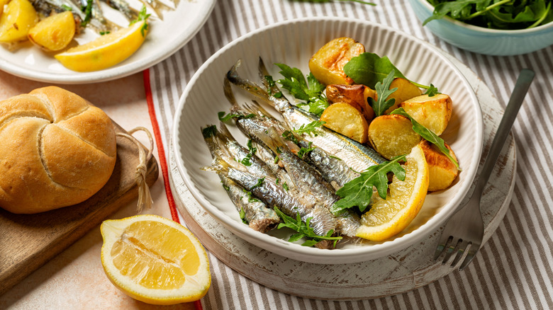 A bowl filled with sardines, lemon, and potatoes