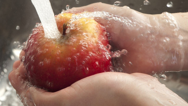 Apple being cleaned under running water