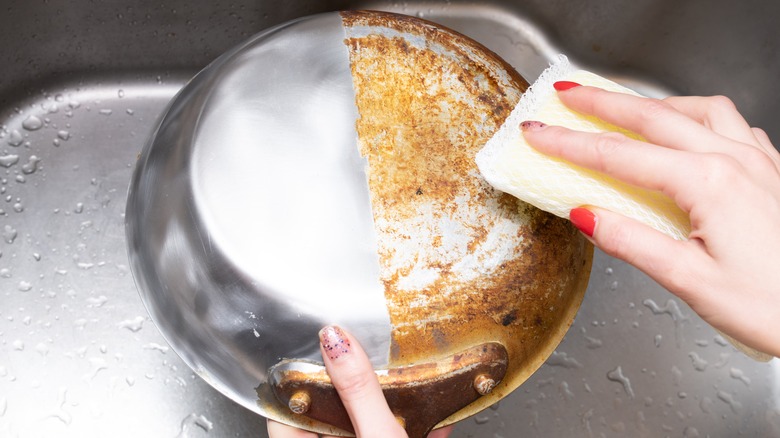 Person washing a dirty aluminum pan