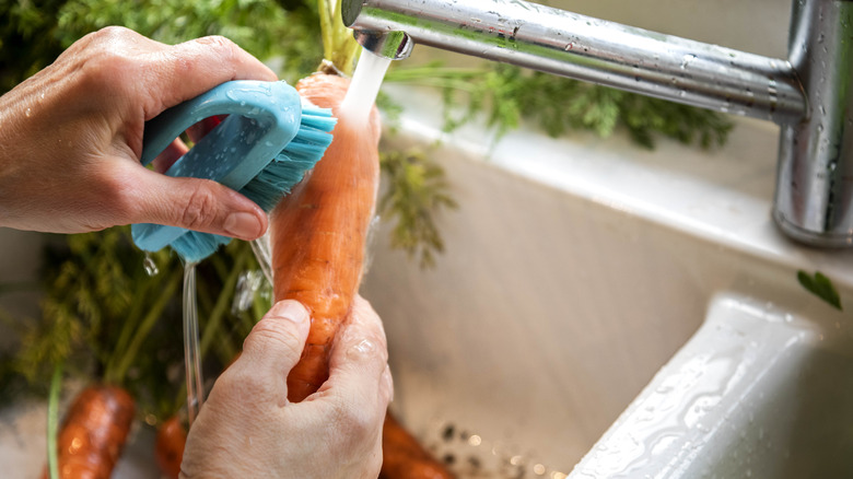 hands scrubbing carrot under faucet