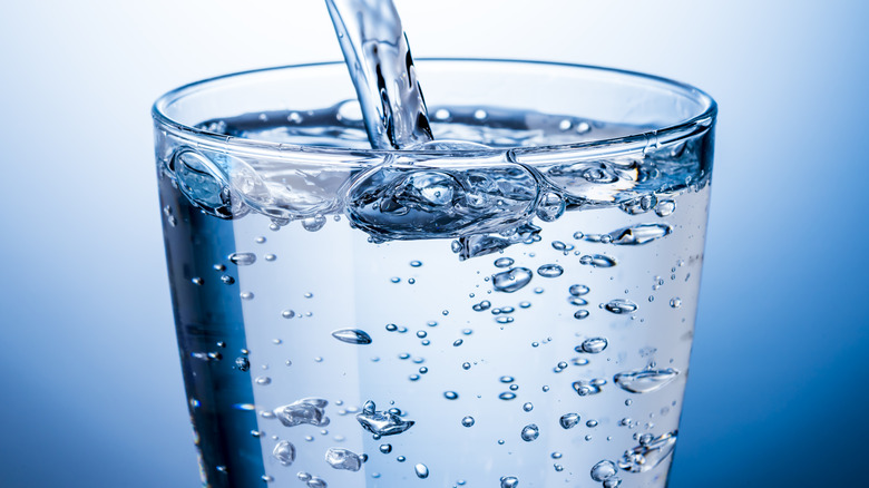 sparkling mineral or club water poured from bottle into glass