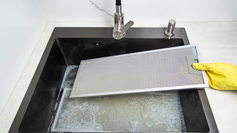 placing grease filter in soapy sink water