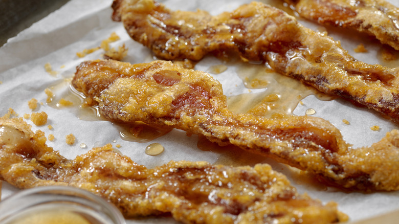 Strips of candied bacon on a baking sheet