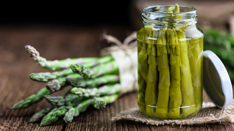 Canned asparagus next to bunch of fresh asparagus