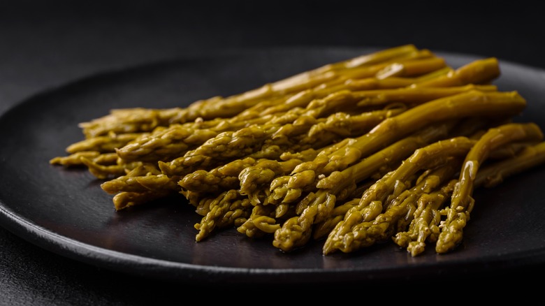 Canned asparagus on a black plate 