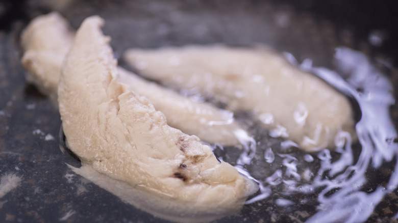chicken fillets under simmering water