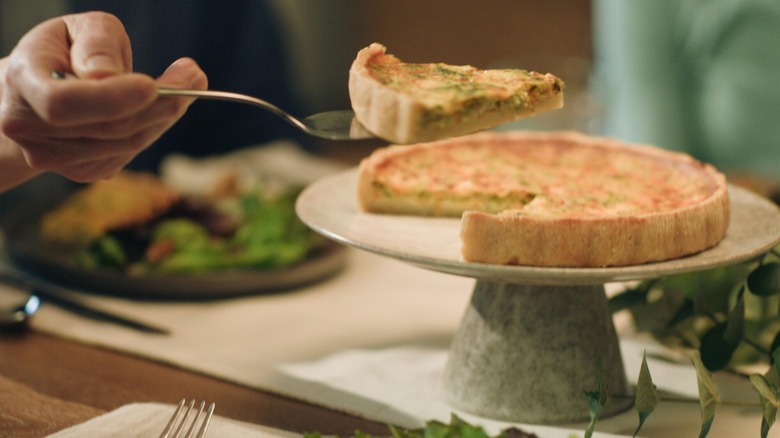 Hand lifting a piece of La Terra Fina Quiche