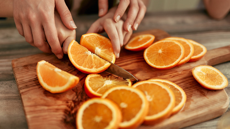 Pair of cooks slicing an orange together