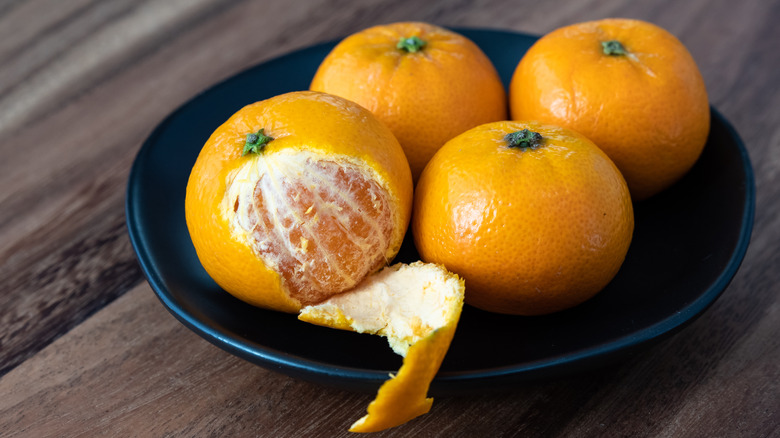 Bowl of oranges, one half-peeled with the pith showing