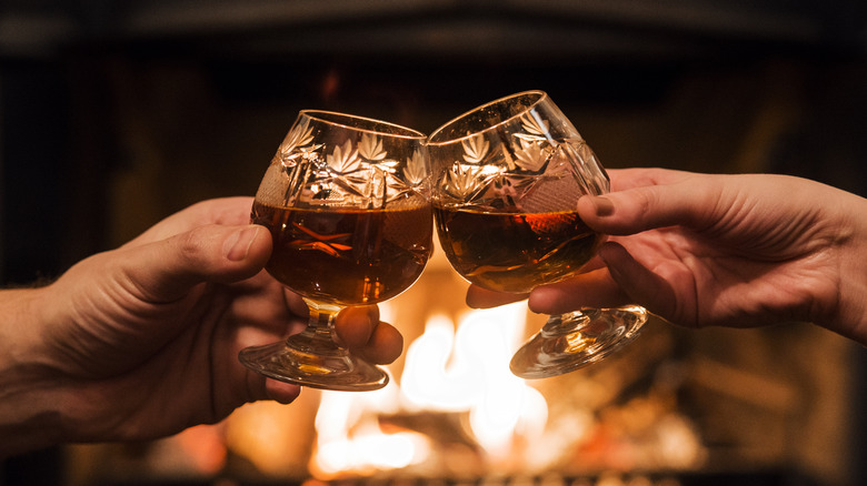 Two people enjoying brandy by fireside