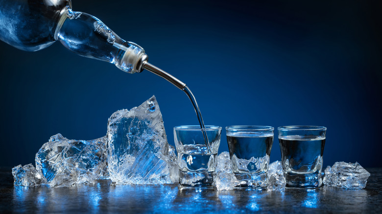 Shot glasses of vodka next to ice.