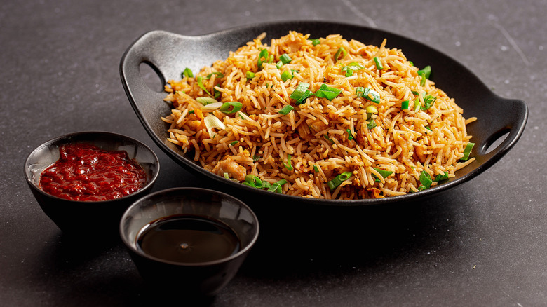 Fried rice in a bowl next to two sauces