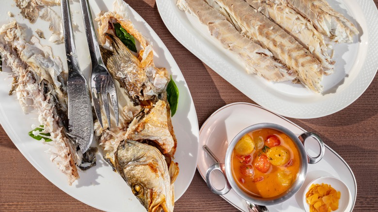 Fish skeleton and meat on separate plates with garnishes