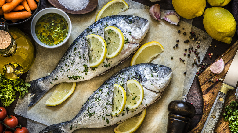 two whole fish on parchment paper with lemon