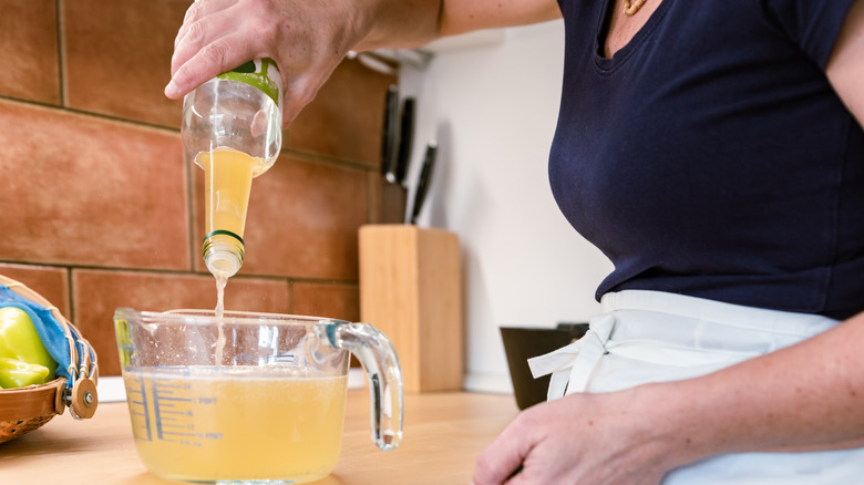 a home cook pours vinegar into a measuring cup