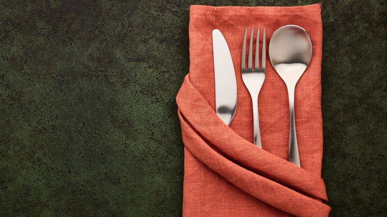 Folded dinner napkin with angled pocket on dark table