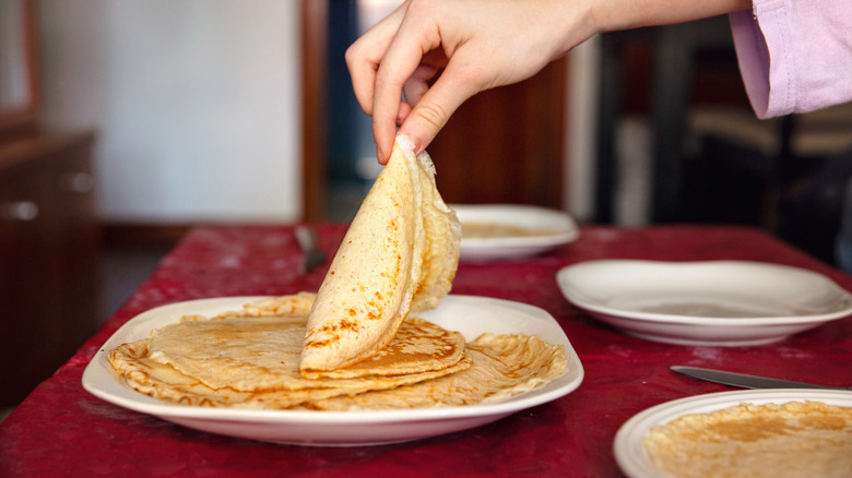 A person taking a crepe from a plate.