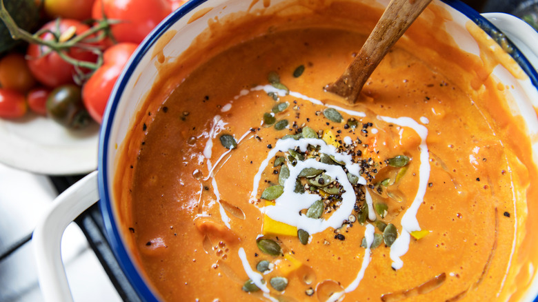 A pot of tomato soup topped with cream.