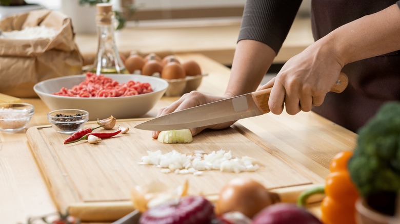 Sharp knife chopping vegetables on cutting board