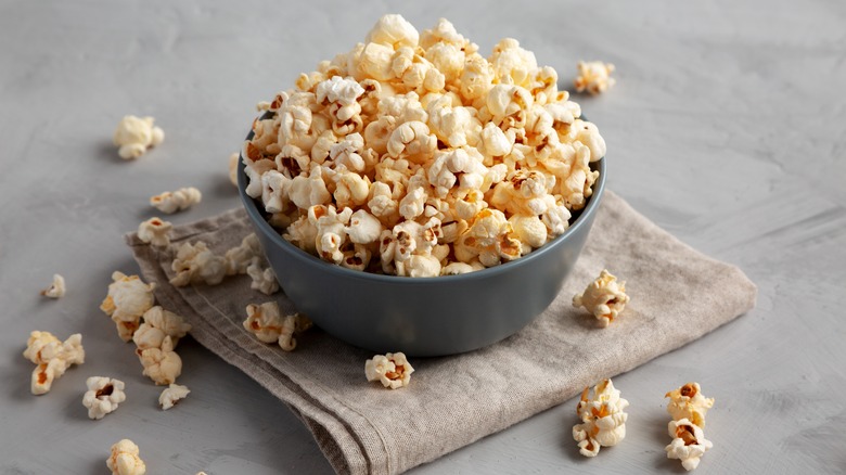 Kettle corn in a small gray bowl on a folded beige napkin with popcorn scattered around the bowl