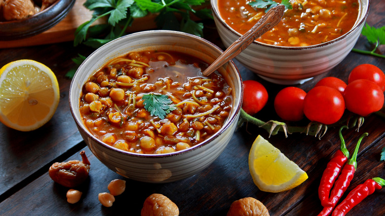 Bowls of harira soup with chickpeas surrounded by ingredients