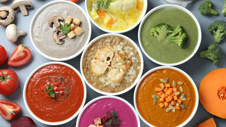Assorted and colorful soups surrounded by veggies