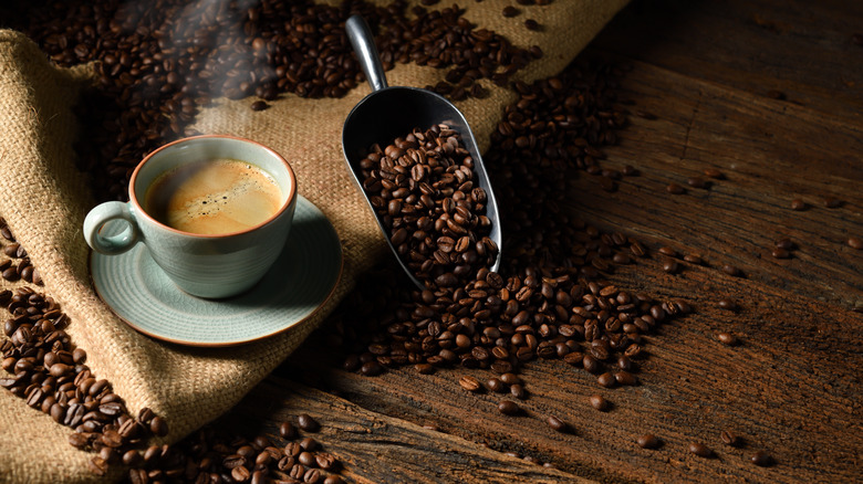 Whole coffee beans next to cup of coffee