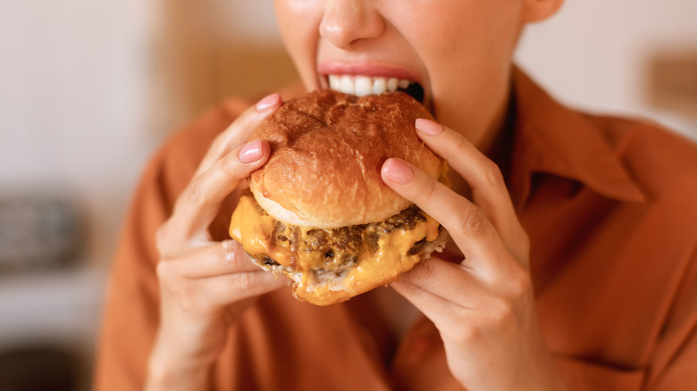 A diner opens wide to take a big bite out of a big burger