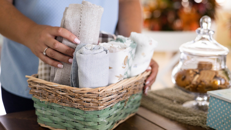 Person storing folded kitchen towels in a cute basket