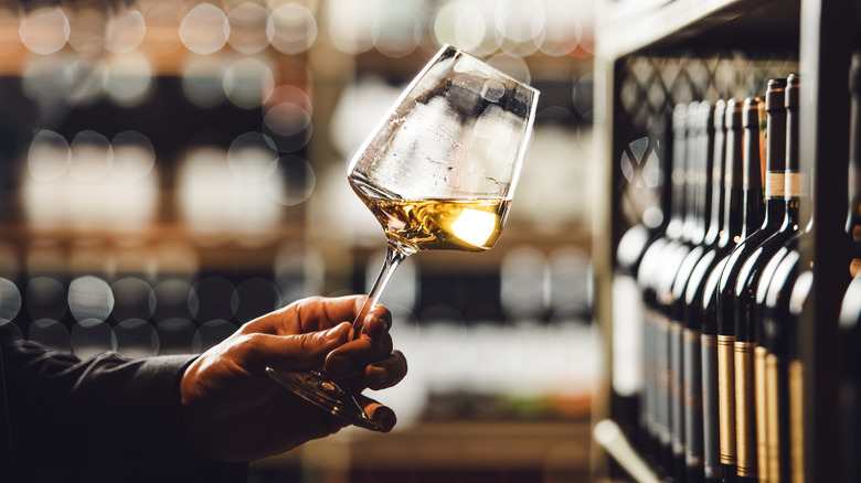 A sommelier holding a glass of white wine.