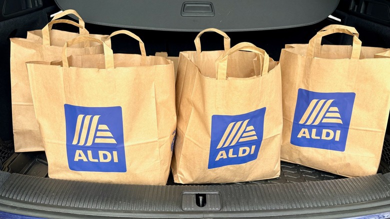 Aldi grocery bags sit in the trunk of a car.