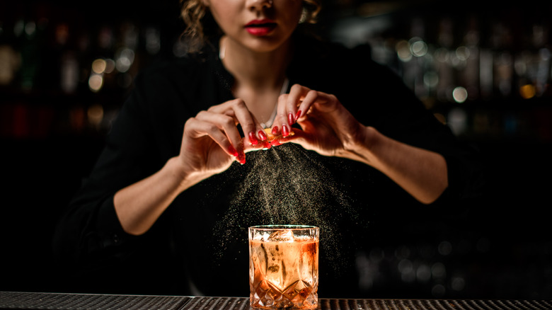 bartender making orange garnished cocktail