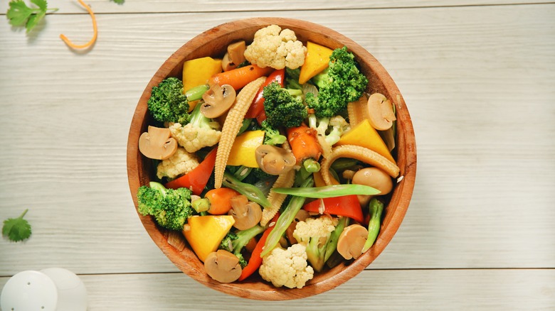 A colorful medley of stir-fried vegetables sit in a wooden bowl