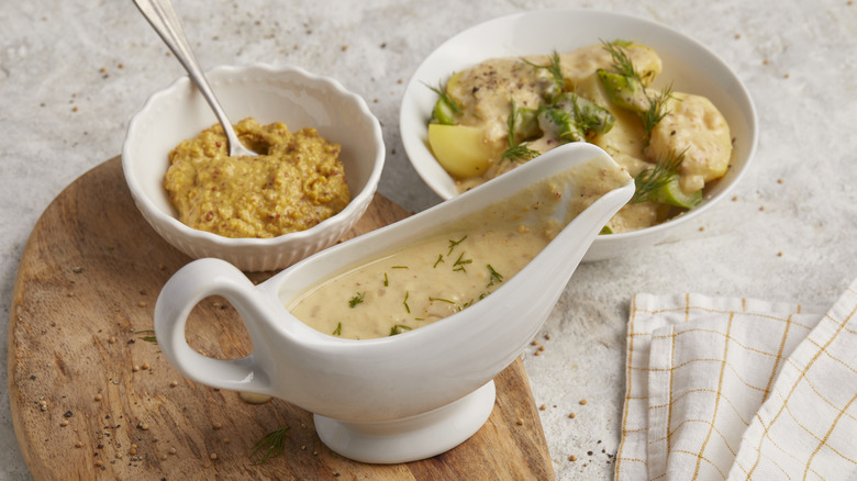 Mustard sauce in a gravy boat, mustard in a small bowl, and a chicken dish with mustard sauce