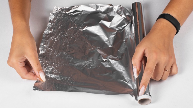Tearing off strip of aluminum foil